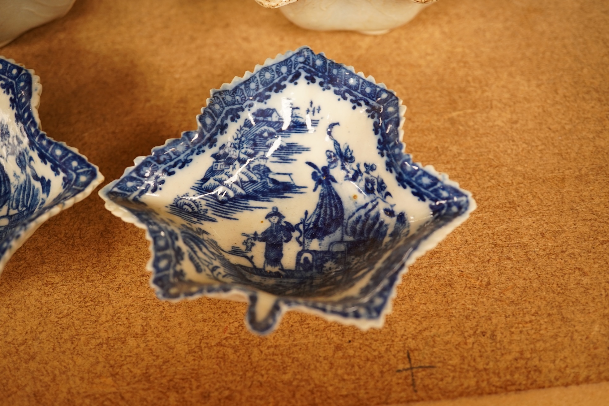 Two late 18th century Worcester or Caughley Cormorant fisherman pattern leaf pickle dishes and two early 19th century blue and white pottery leaf pickle dishes, largest 14.5cm long.